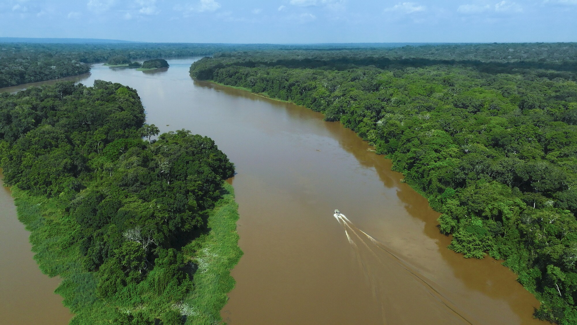 Aerial drone shot of the boat going upriver between the forests. (National Geographic for Disney+/Bertie Gregory)