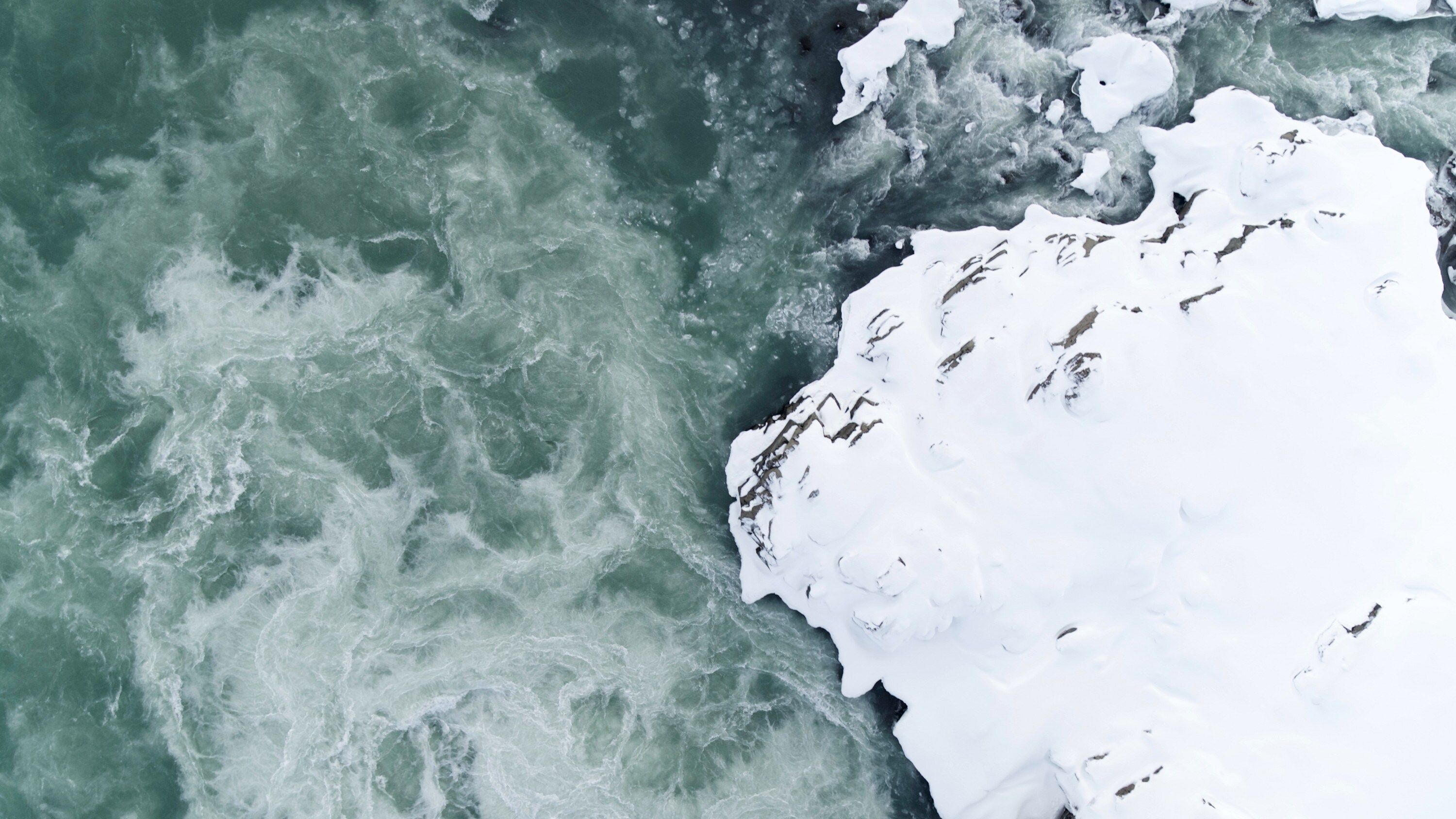 Aerial view of a flowing icy river with a snow-covered riverbank in Jökulsárlón National Park, Iceland. (National Geographic for Disney+)