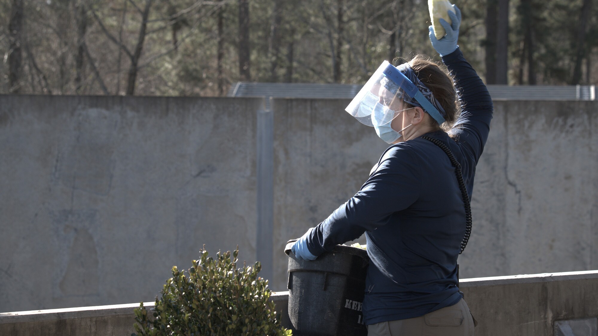 Caregiver Ellen Brady-McGaughey in PPE overlooking enclosure with bucket of cabbages. (National Geographic/Virginia Quinn)