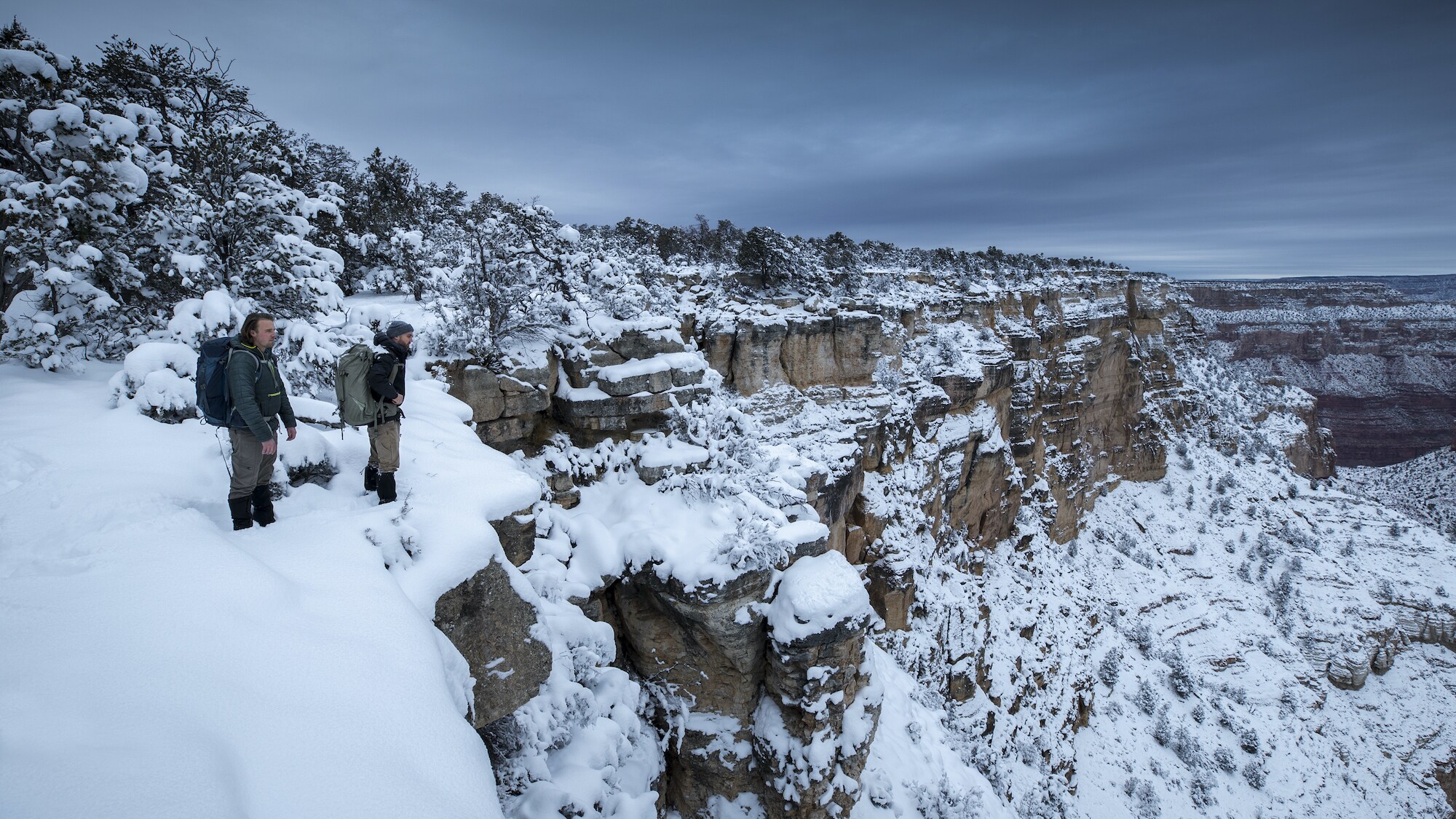 Wildlife Cameramen Jake Davis and Pete Matthews survey the Grand Canyon, AZ, after heavy snowfall, on their hike in to check and maintain camera traps deployed along its rim. (National Geographic for Disney+/Andrew Studer)