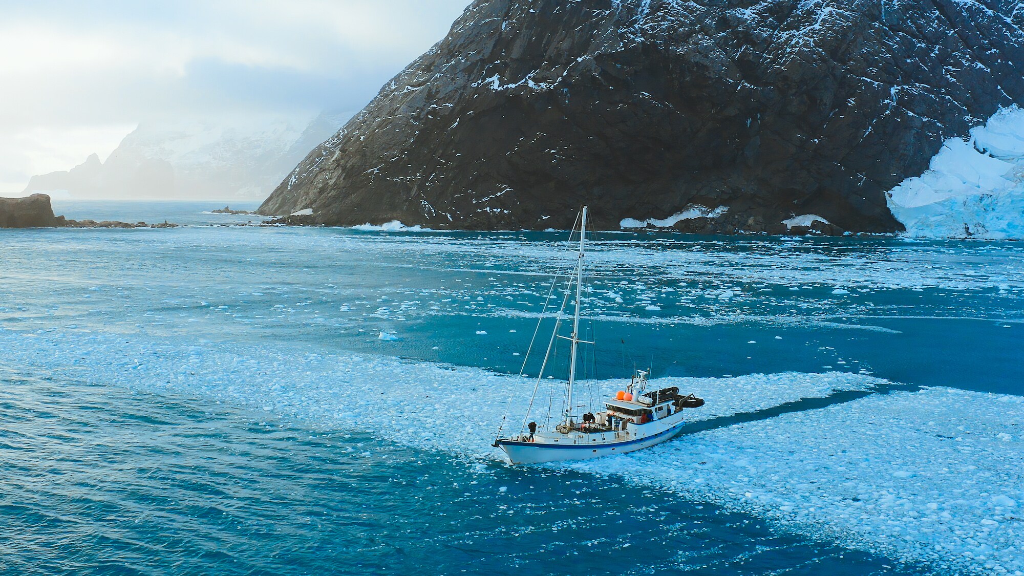 The Australis pushes out to sea to look for whales from an anchorage at Point Wild, Elephant Island. (Credit: National Geographic/Bertie Gregory for Disney+)