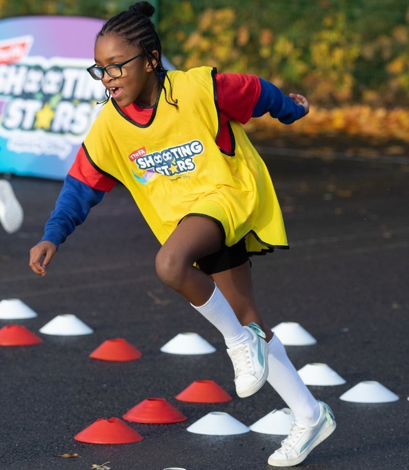 A girl in a yellow bib doing a shuttle run