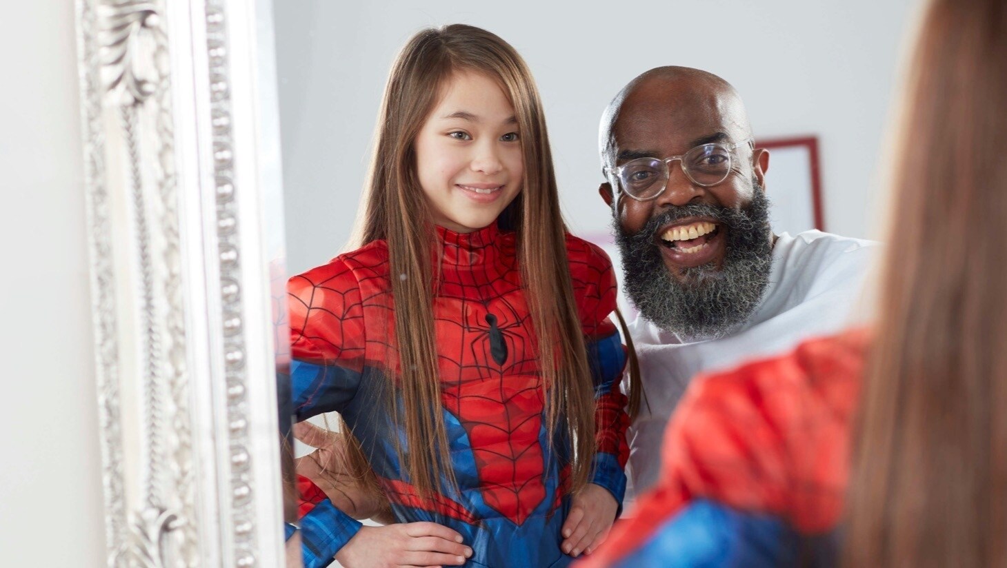 Bambina con il costume di Spiderman shopDisney davanti allo specchio con il padre.