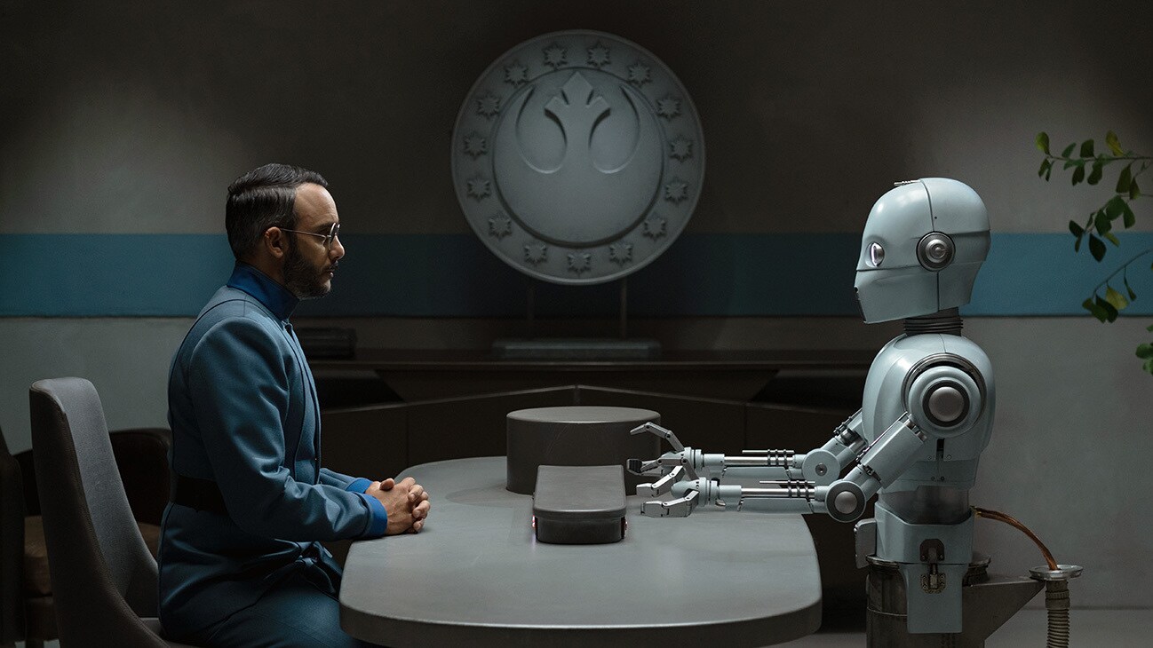 Dr. Pershing (Omid Abtahi) is interviewed by a parole droid in the Disney+ Original series, Star Wars: The Mandalorian, Season 3.