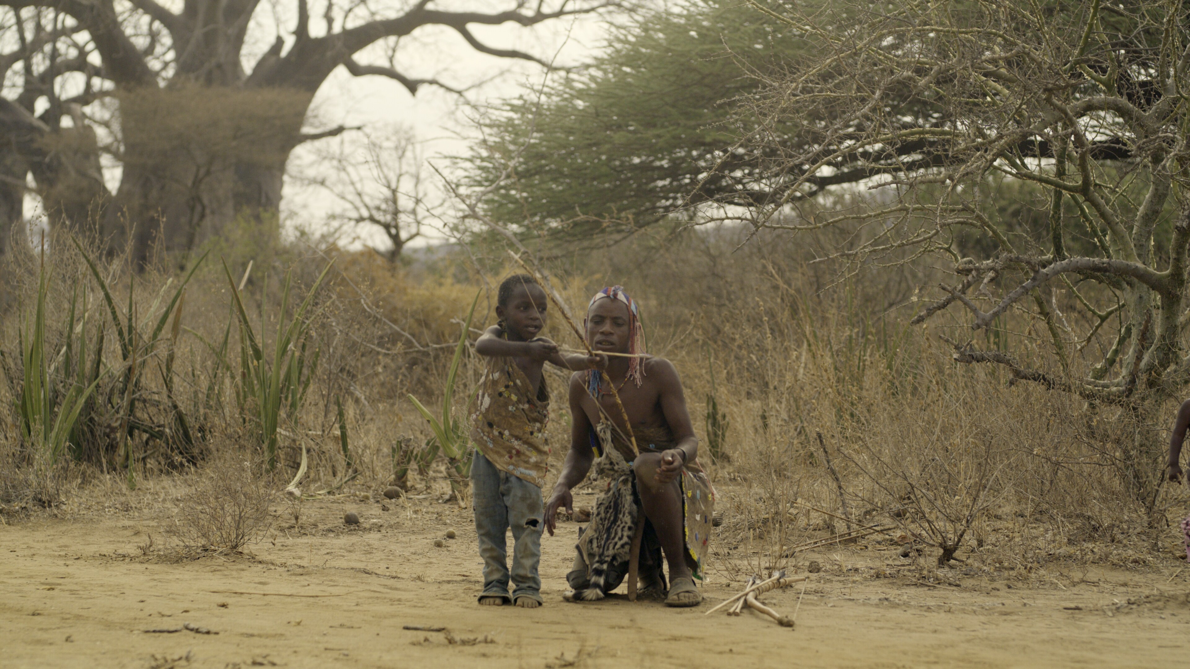 A Hadza father and son practice shooting the bow and arrow. (National Geographic for Disney+)