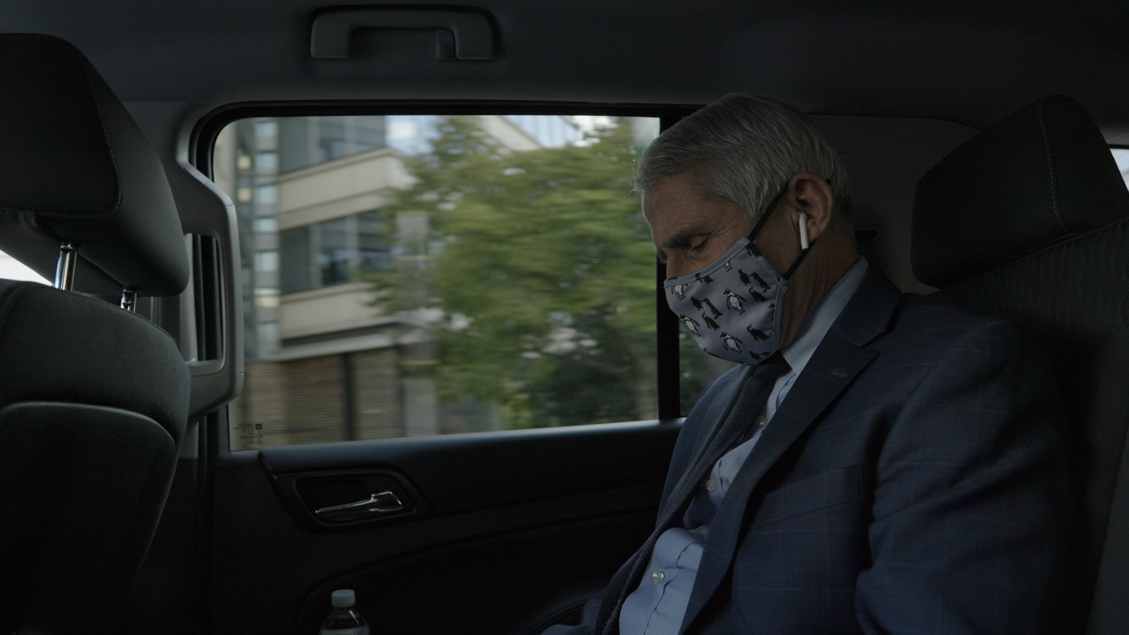 Dr. Anthony Fauci talks on the phone in his security detail car. Dr. Fauci received security after receiving death threats in 2020.  (National Geographic for Disney+)