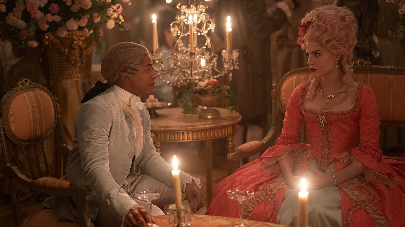  Marie Antoinette (actor Lucy Boynton) and Jospeh (actor Kelvin Harrison Jr.) sitting at a table in the 20th Century Studios movie, "Chevalier."