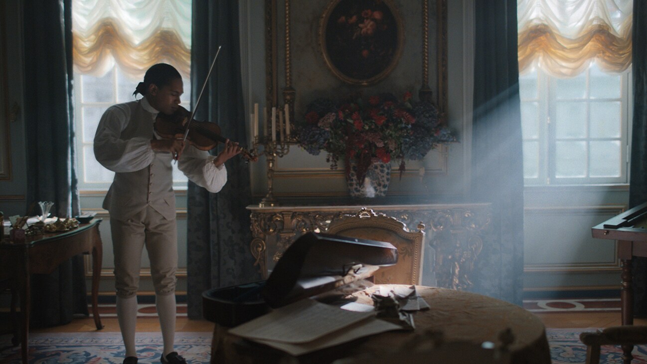 Joseph (actor Kelvin Harrison Jr.) playing the violin in a room in the 20th Century Studios movie, "Chevalier."