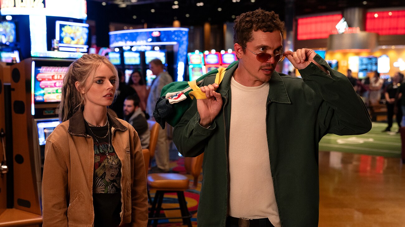 Edie (Samara Weaving) in a casino with John (Karl Glusman) in a scene from 20th Century Studios' EENIE MEANIE. Photo courtesy of 20th Century Studios. © 2025 20th Century Studios. All Rights Reserved.
