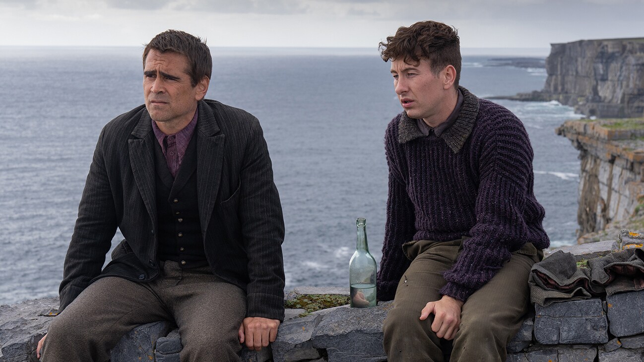 Pádraic Súilleabháin (actor Colin Farrell) and Dominic Kearney (actor Barry Keoghan)sitting on a stone wall by the water from the Searchlight Pictures movie "The Banshees of Inisherin".