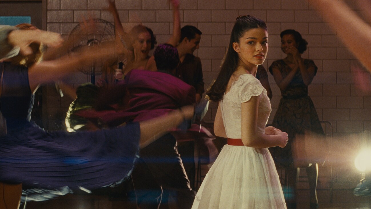 Actor Rachel Zegler looking over her shoulder on a dance floor from the 20th Century Studios movie "West Side Story".