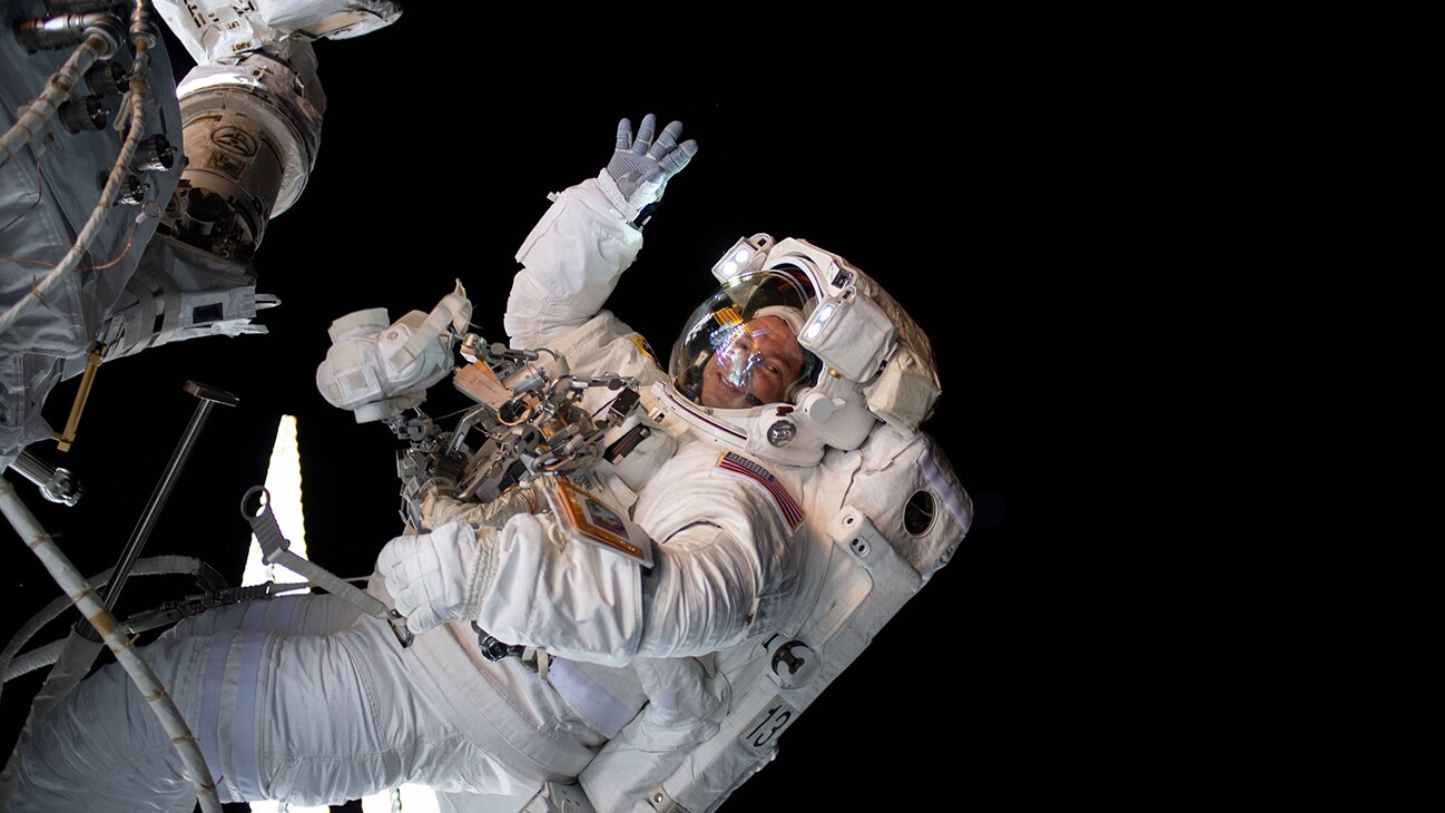 AMONG THE STARS - (Aug. 21, 2019) - NASA astronaut Andrew Morgan waves as he is photographed during a spacewalk to install the International Space Station’s second commercial crew vehicle docking port, the International Docking Adapter-3 (IDA-3).  (NASA)  ANDREW MORGAN