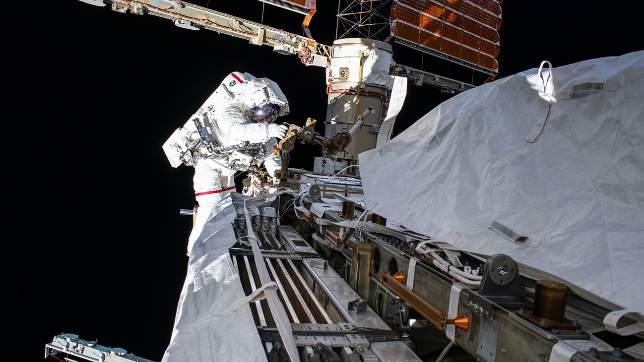 AMONG THE STARS - (Oct. 11, 2019) - NASA astronaut Andrew Morgan works while tethered on the Port 6 truss segment of the International Space Station to replace older hydrogen-nickel batteries with newer, more powerful lithium-ion batteries. The batteries store and distribute power collected from the station's basketball court-sized solar arrays directly behind Morgan. (NASA)  ANDREW MORGAN