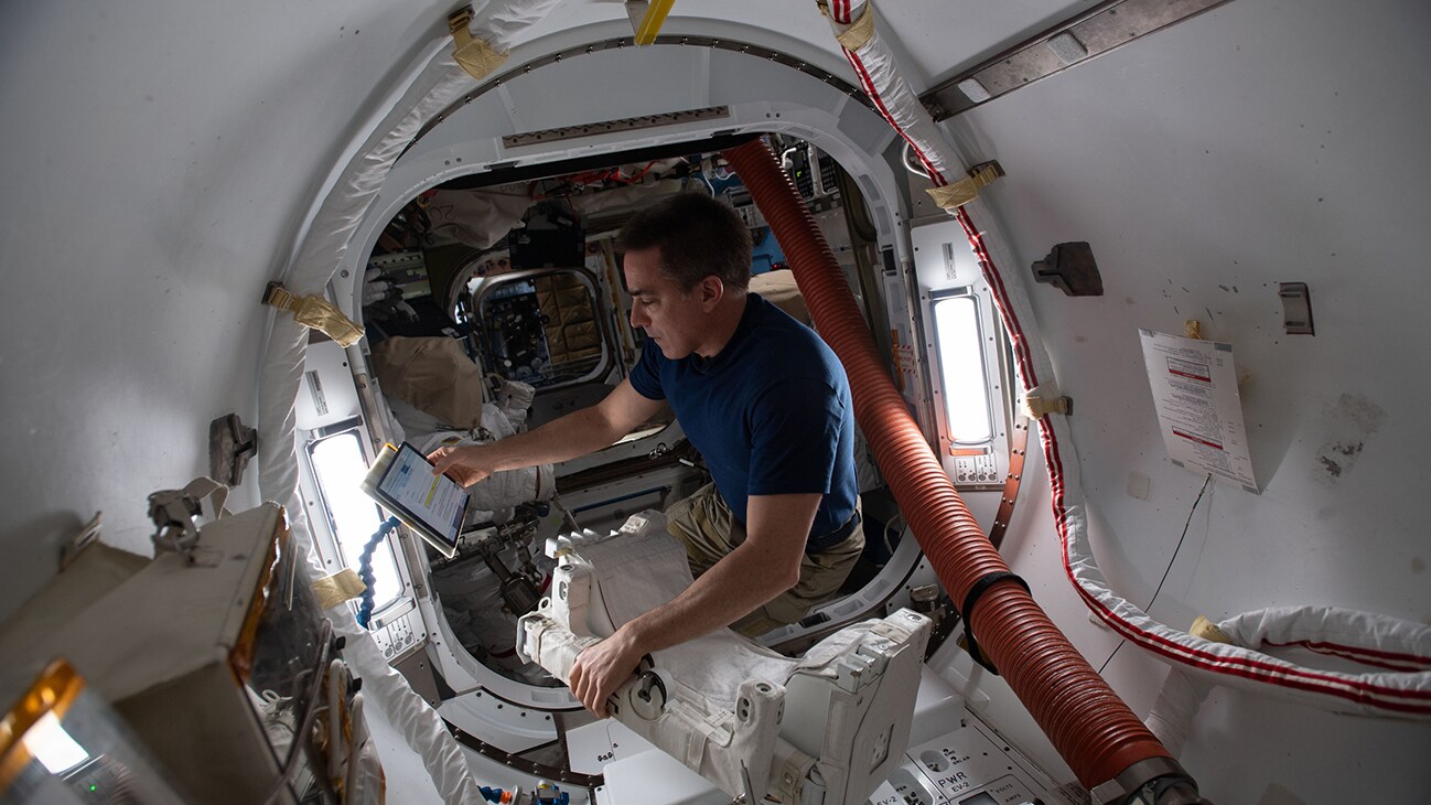 AMONG THE STARS - (June 24, 2020) - NASA astronaut and Expedition 63 Commander Chris Cassidy reviews maintenance procedures on a computer while working on U.S. spacesuit components inside the International Space Station's Quest airlock. (NASA)  CHRIS CASSIDY