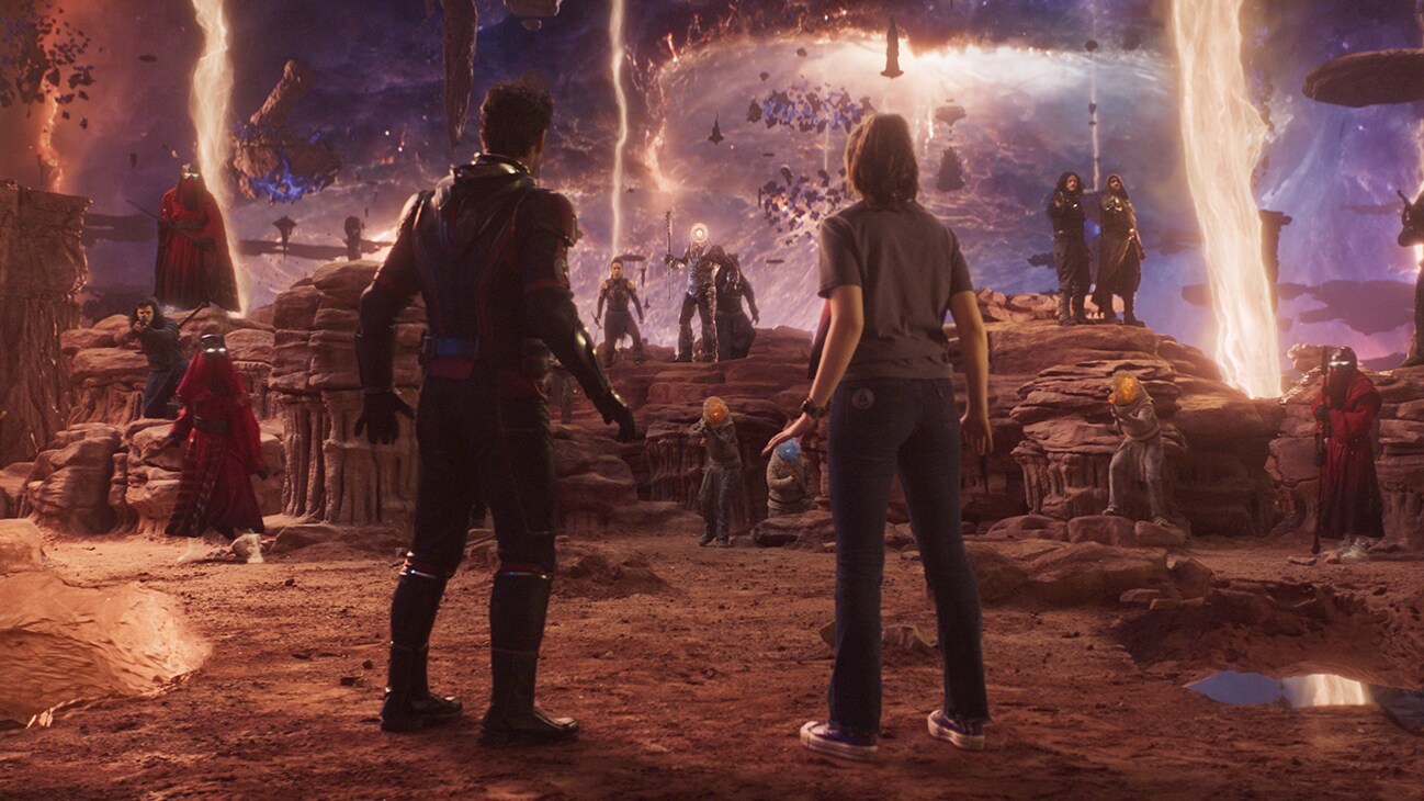 Ant-Man (actor Paul Rudd) and Cassie Lang (actor Kathryn Newton) stand before a group of characters from the Quantum Realm. From the film, "Marvel Studios' Ant-Man and the Wasp: Quantumania".