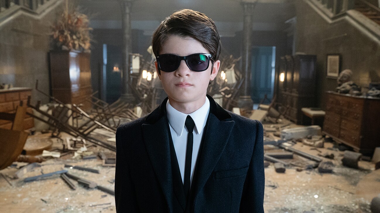 Ferdia Shaw as Artemis Fowl standing in a room of debris and disarray.