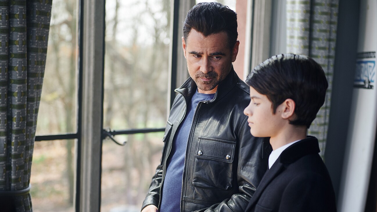 Colin Ferrell as Artemis Fowl Sr. and Ferdia Shaw as the junior Artemis Fowl, together standing by a window, in the movie ARTEMIS FOWL.