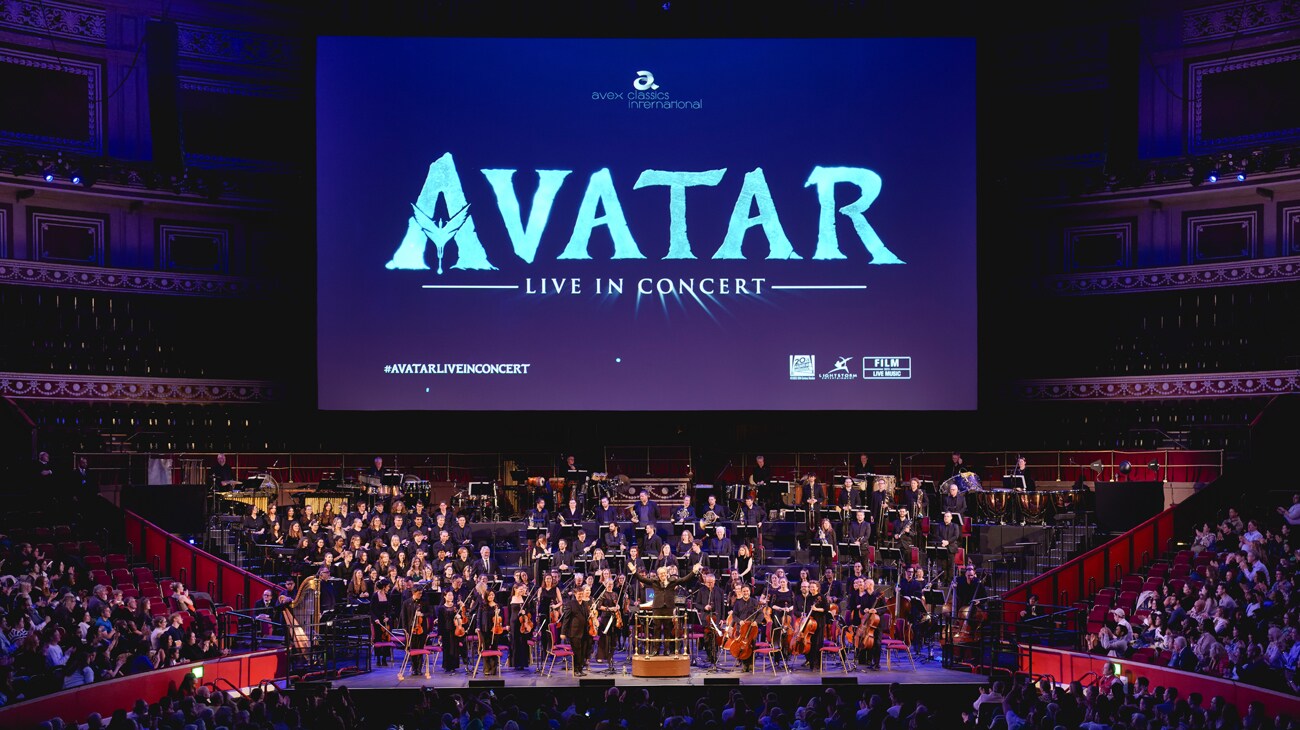 Image of symphony and audience with Avatar: Live In Concert above on a theater screen.