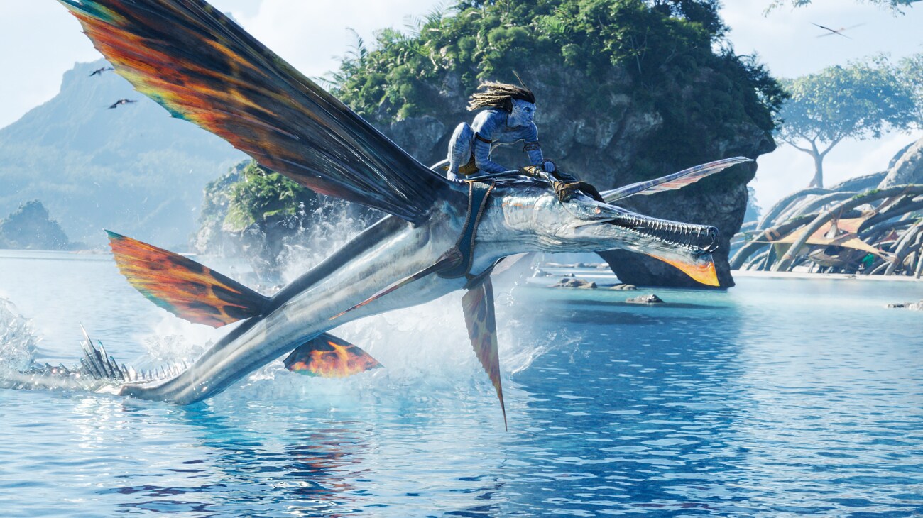 A skimwing carrying Jake Sully leaps out of the water.