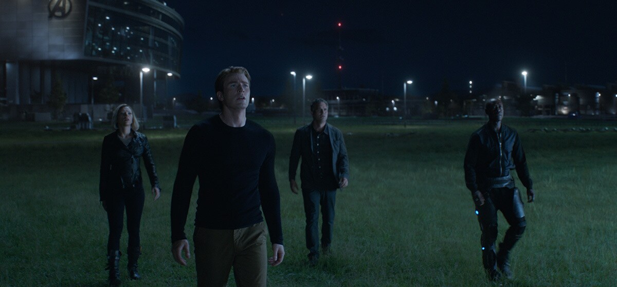 Black Widow/Natasha Romanoff (Scarlett Johansson), Captain America/Steve Rogers (Chris Evans), Bruce Banner (Mark Ruffalo), and War Machine/James Rhodes (Don Cheadle) on the grass in front of Avengers Compound and looking at the sky