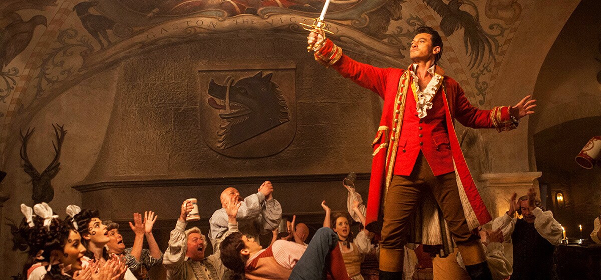 Luke Evans (as Gaston) standing on top of a table in a bar in the movie "Beauty and the Beast"