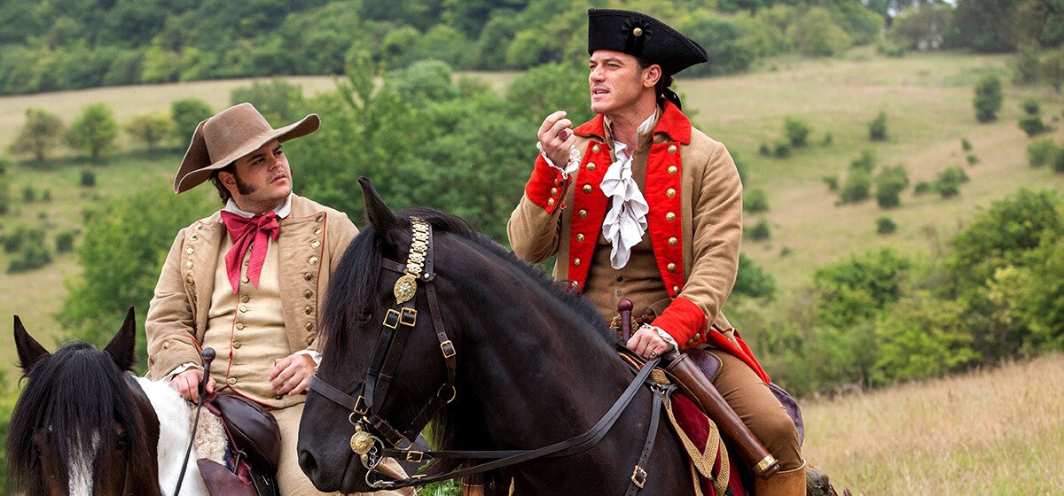 Josh Gad (as LeFou) and Luke Evans (as Gaston) on horseback in the county side in "Beauty and the Beast"