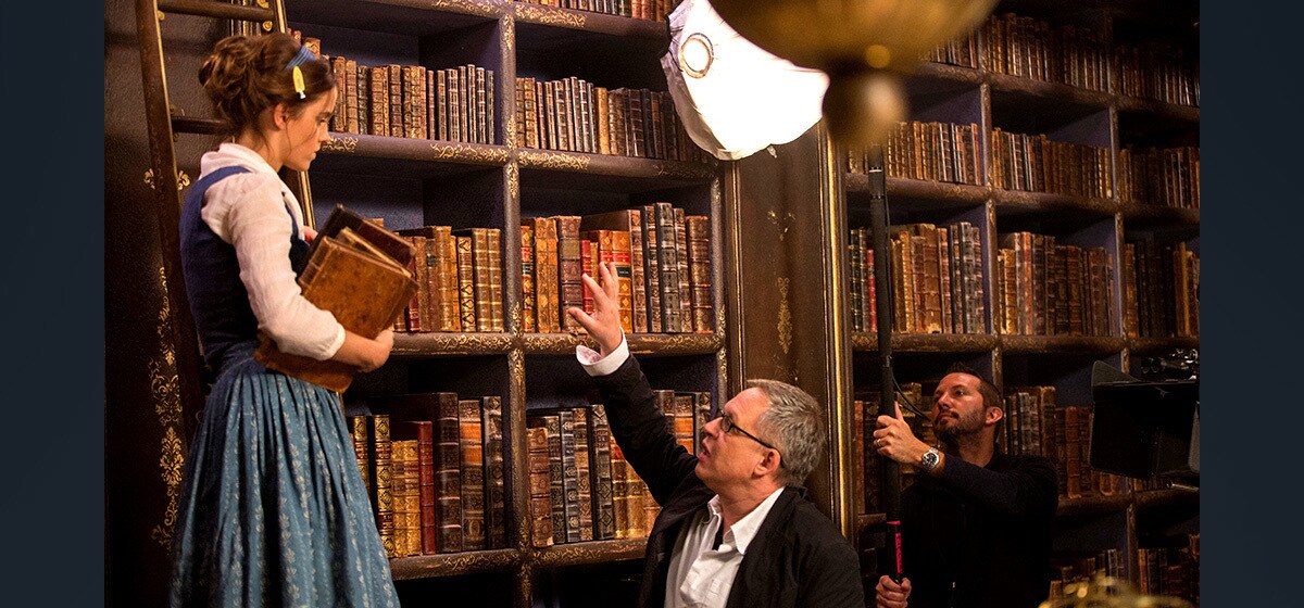 Director Bill Condon instructs Emma Watson (Belle) as she stands on a ladder in "Beauty and the Beast"