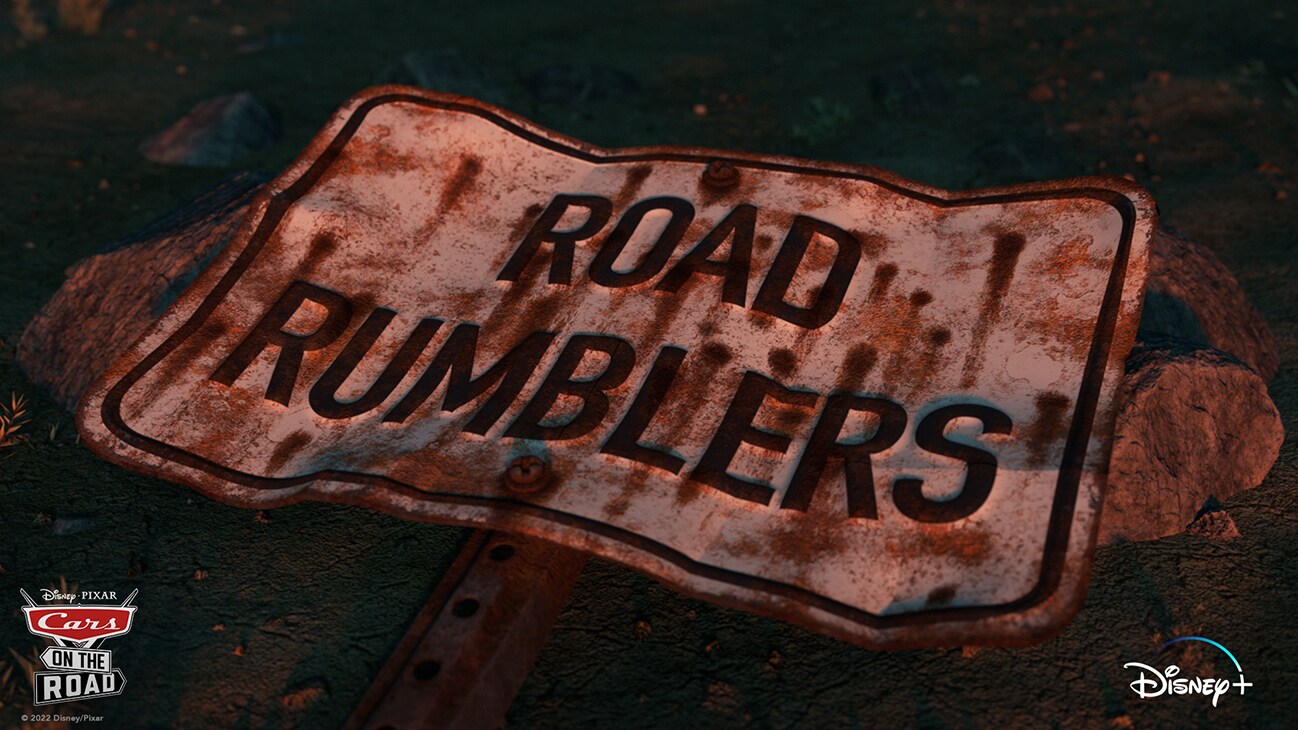 Disney•Pixar | Cars on the Road | "Road Rumblers" title card written on a rusty, dirty, and bent sign on the ground | Disney+