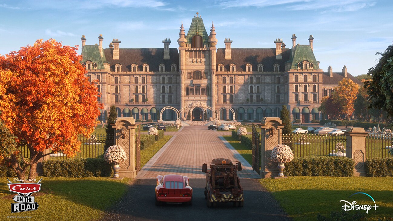 Lightning McQueen (voice of Owen Wilson) and Mater (voice of Larry the Cable Guy) at the gates of a mansion from the Disney+ Original series "Cars on the Road".