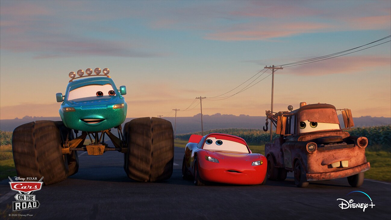 Lightning McQueen (voice of Owen Wilson) and Mater (voice of Larry the Cable Guy) on the road next to a car with monster truck sized wheels from the Disney+ Original series "Disney•Pixar Cars on the Road".