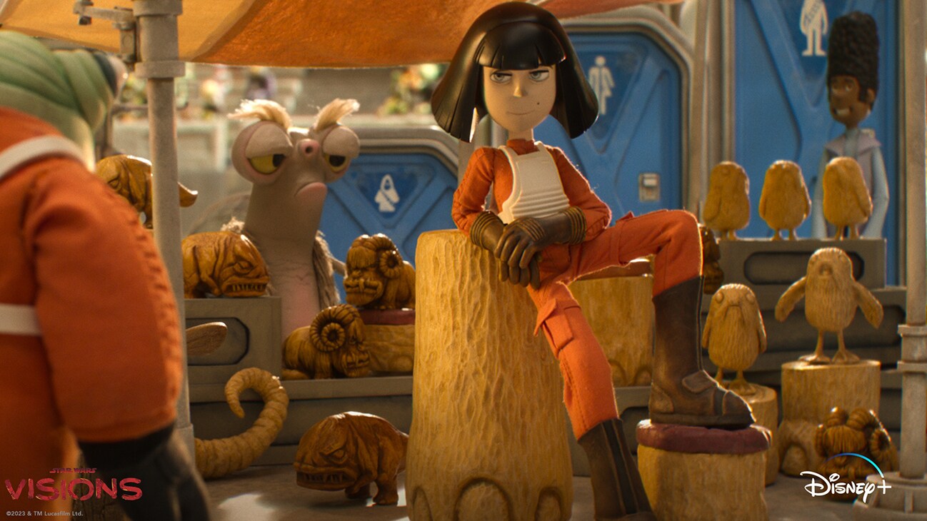 A female Rebel Alliance fighter pilot surrounded by several wood sculpted creatures from the Aardman animated short, “I Am Your Mother”, part of Star Wars Visions Volume 2 streaming May 4 on Disney+.