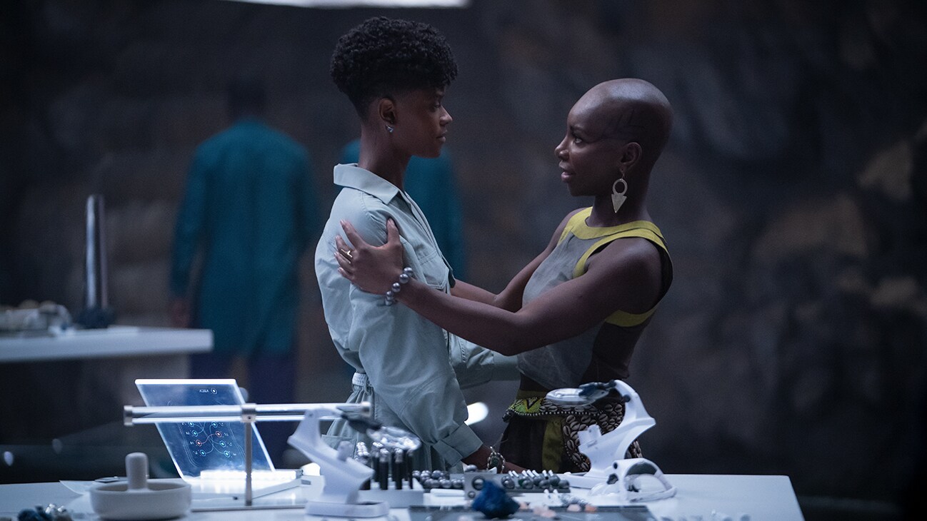 Aneka (actor Michaela Coel) holds Shuri (actor Letitia Wright) as they talk in a lab. From the film, Marvel Studios' Black Panther: Wakanda Forever.