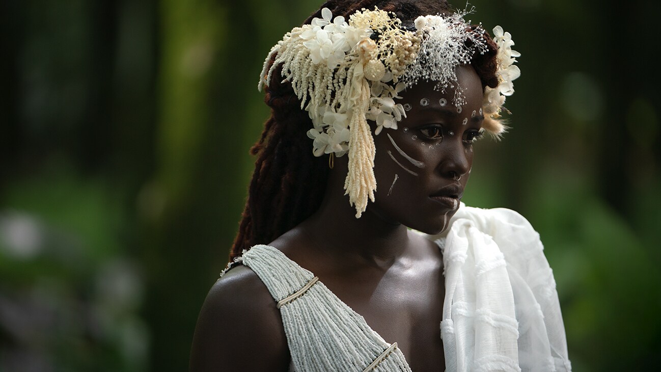 Nakia (actor Lupita Nyong'o) is dressed in white, wearing a white crown of flowers. From the film, Marvel Studios' Black Panther: Wakanda Forever.
