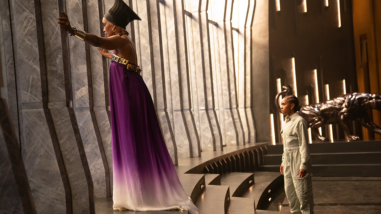 Queen Ramonda (actor Angela Bassett) gazes out from the windows as Riri Williams (actor Dominique Thorne) stands behind her. From the film, Marvel Studios' Black Panther: Wakanda Forever.