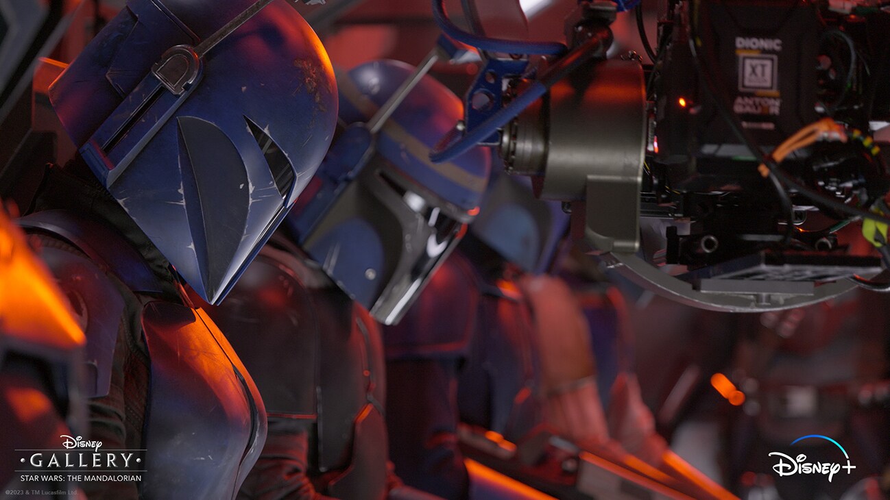 A camera pointing at several Mandalorians sitting in a row as they prepare to be dropped from a starship onto Mandalore from the Disney+ Original series, "Disney Gallery - Star Wars: The Mandalorian Season 3."