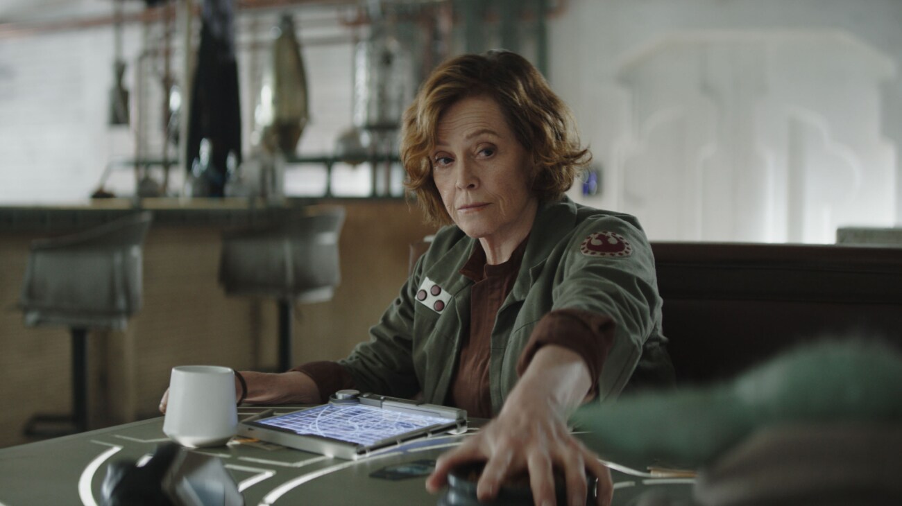 (L-R) Colonel Ward (Sigourney Weaver) and Grogu in Lucasfilm's THE MANDALORIAN AND GROGU. Photo courtesy of Lucasfilm. © 2025 Lucasfilm Ltd™. All Rights Reserved.