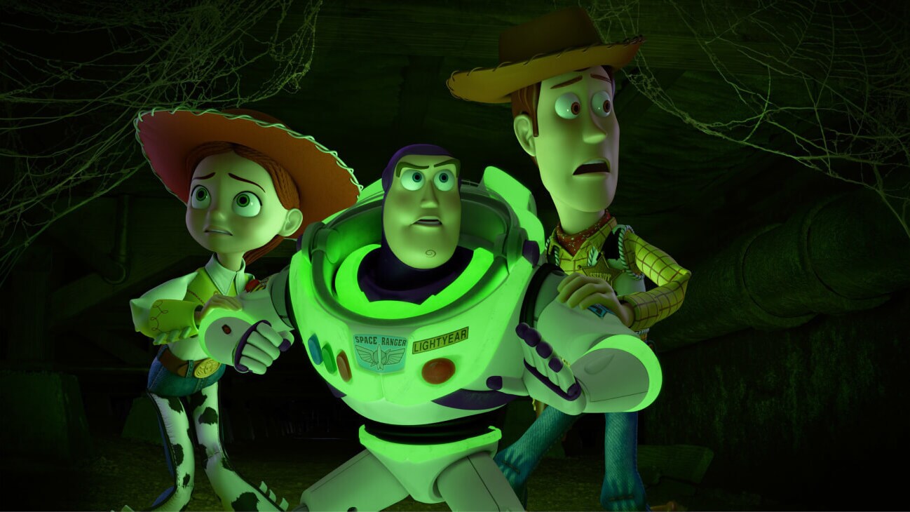 Jessie (Joan Cusack), a glowing Buzz Lightyear (Tim Allen), and Sheriff Woody (Tom Hanks) walking cautiously through a dark vent tunnel filled with cobwebs in Toy Story of Terror! (2013).