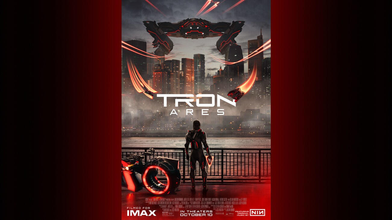 Image of an individual standing next to a lightcycle while holding a triangular disc. The individual is staring at a city across a body of water. A Recognizer vehicle is hovering over the city.