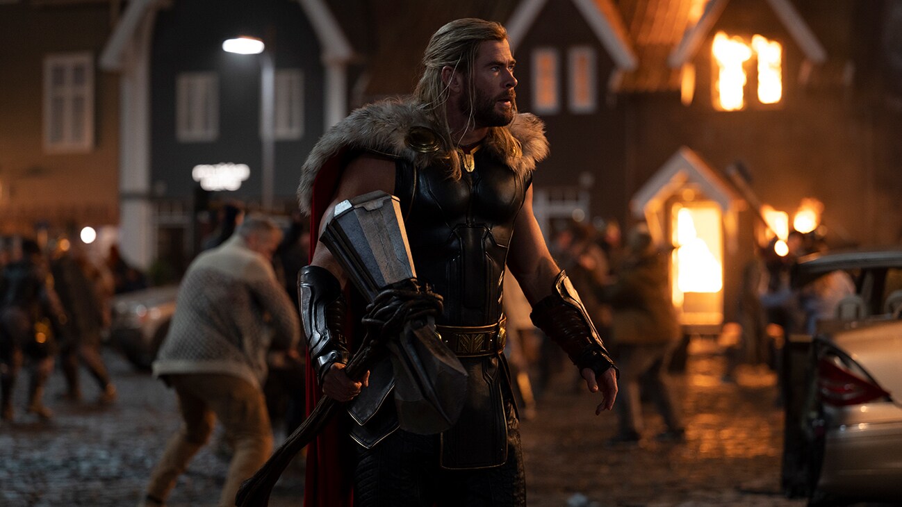 Thor (actor Chris Hemsworth) stands in a town under attack in Marvel Studios' Thor: Love and Thunder.