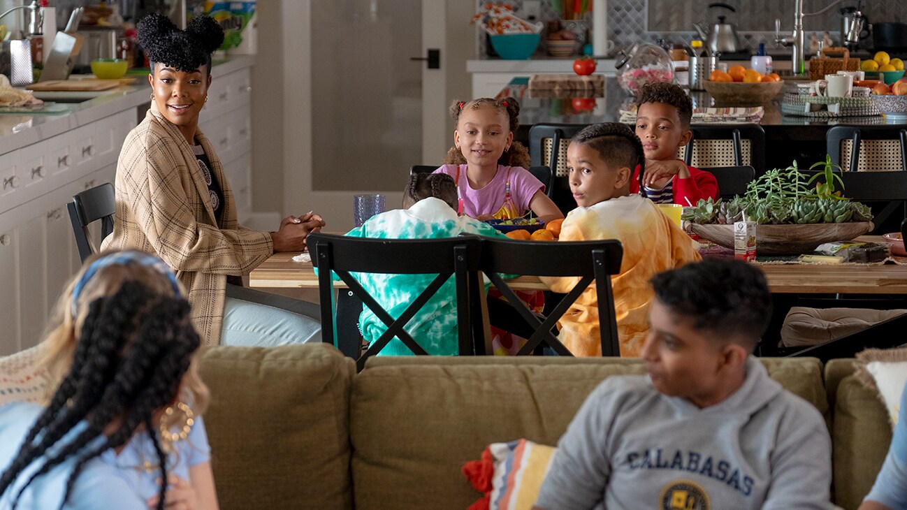 The cast of the Disney+ Original movie "Cheaper by the Dozen" sitting around the dinner table.