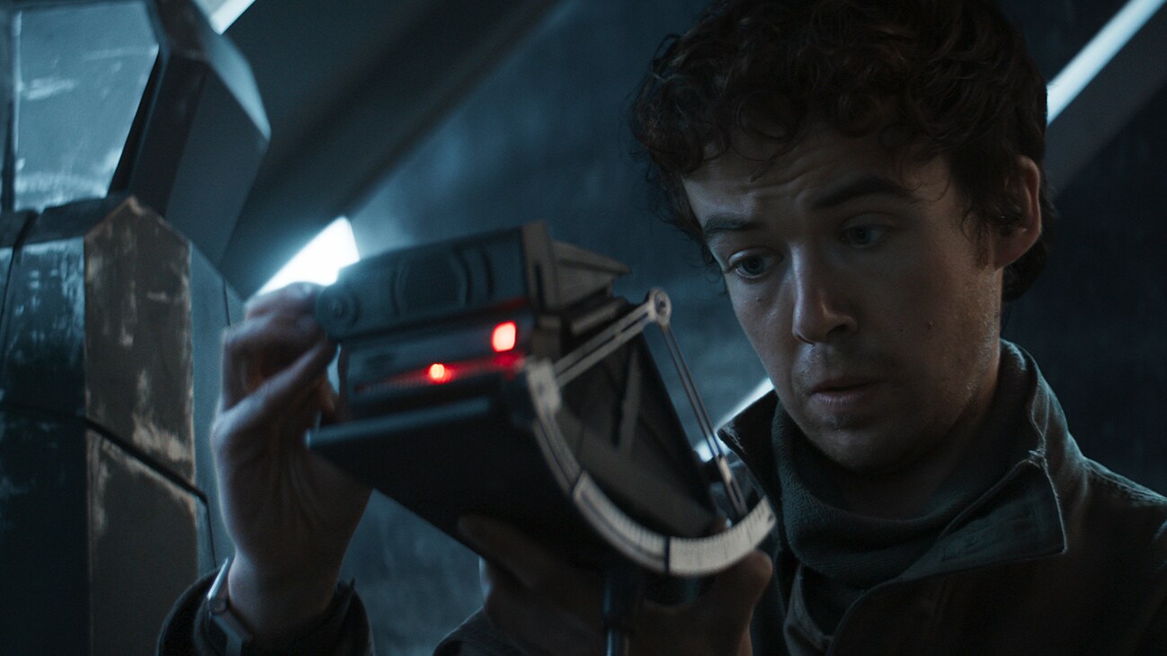 Karis Nemik (actor Alex Lawther) looking at a handheld electronic device from the Disney+ Original series, "Andor."