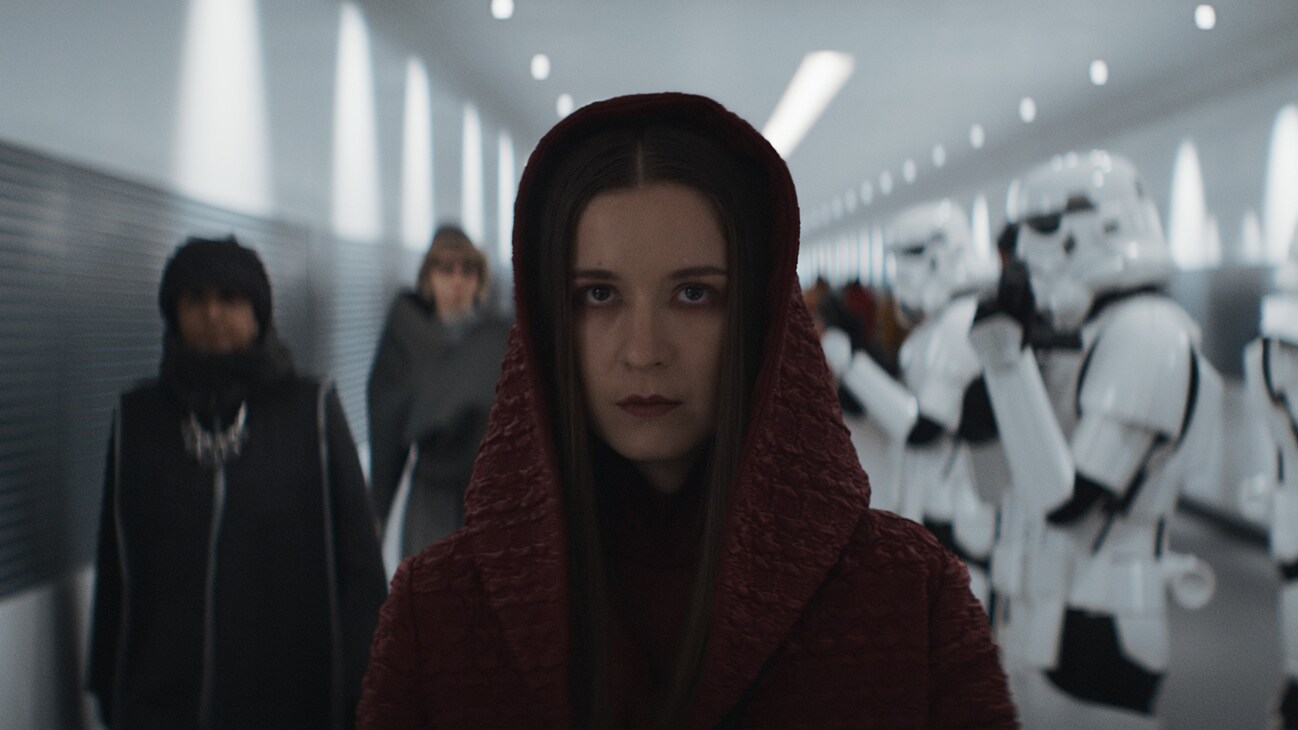 A hooded woman walking down a corridor by Imperial stormtroopers from the Disney+ Original series, "Andor."