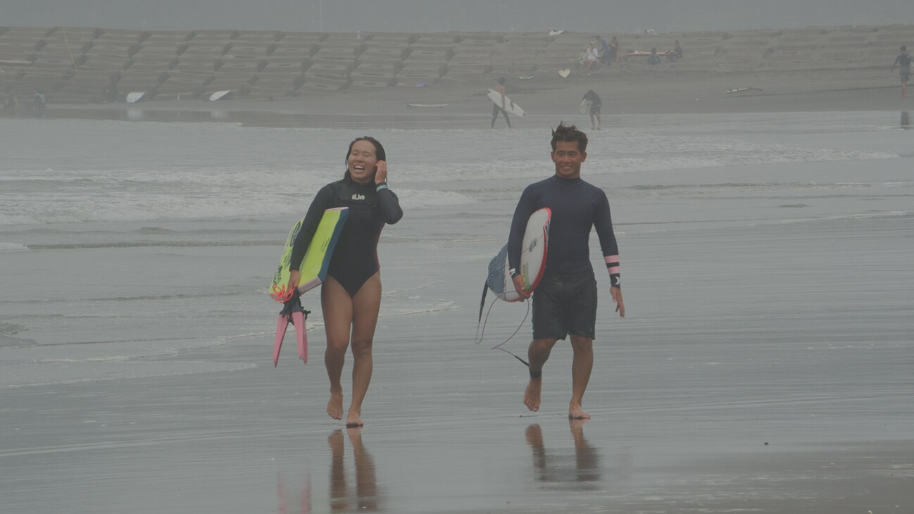 Two surfers walking on the beach.