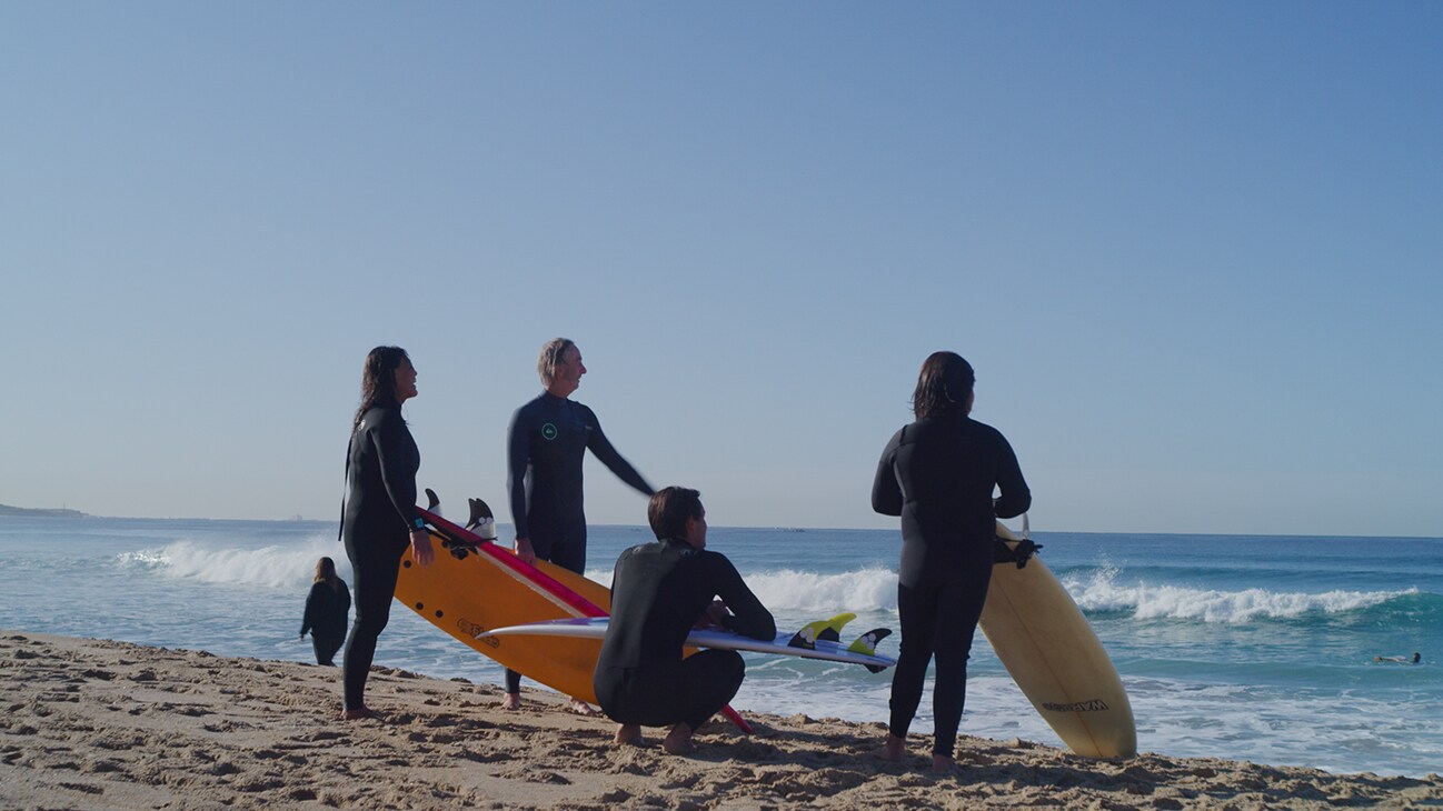 A group of surfers looks off toward the waves.