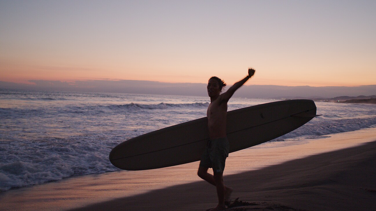 A surfer cheers as they make their way into the water.
