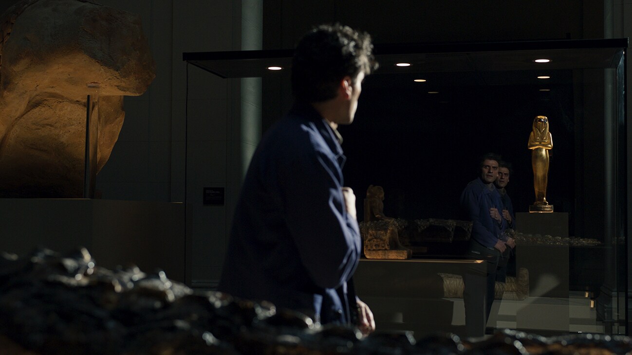 Image of Steven Grant (actor Oscar Isaac) staring at a golden Egyptian statue in a mirror from Marvel Studios' "Moon Knight".