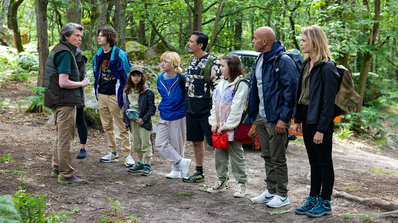 A group of adults and children in the woods.