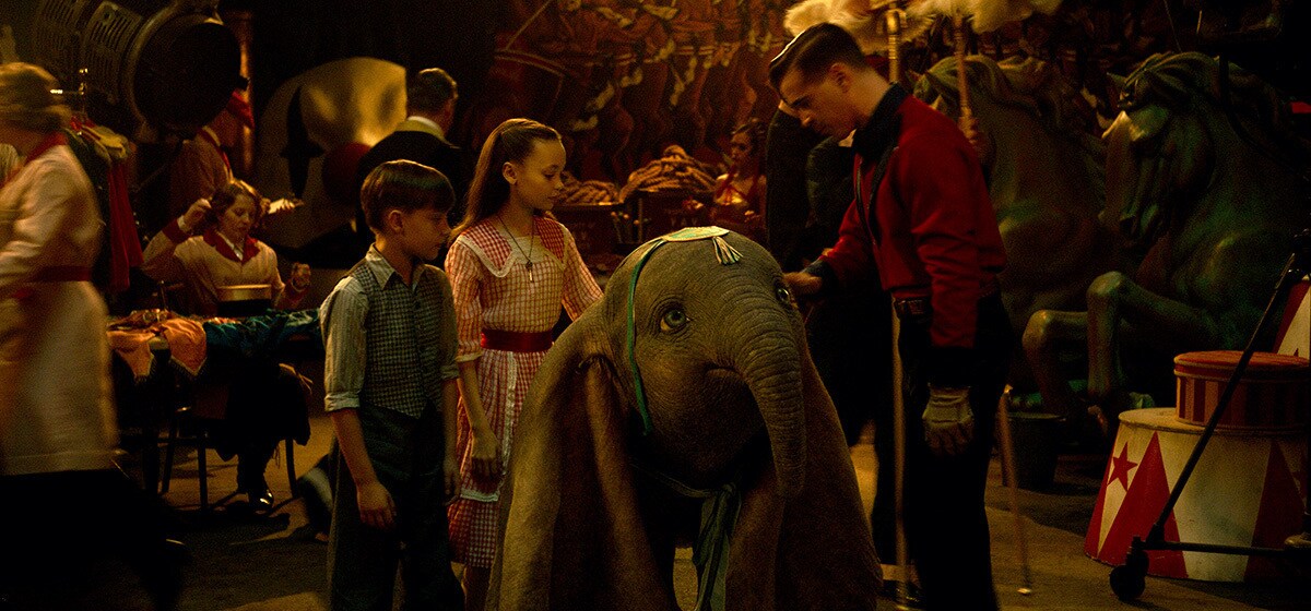 Colin Farrell (Holt Farrier), Nico Parker (Milly Farrier) and Finley Hobbins (Joe Farrier) stands with Dumbo from the movie "Dumbo"