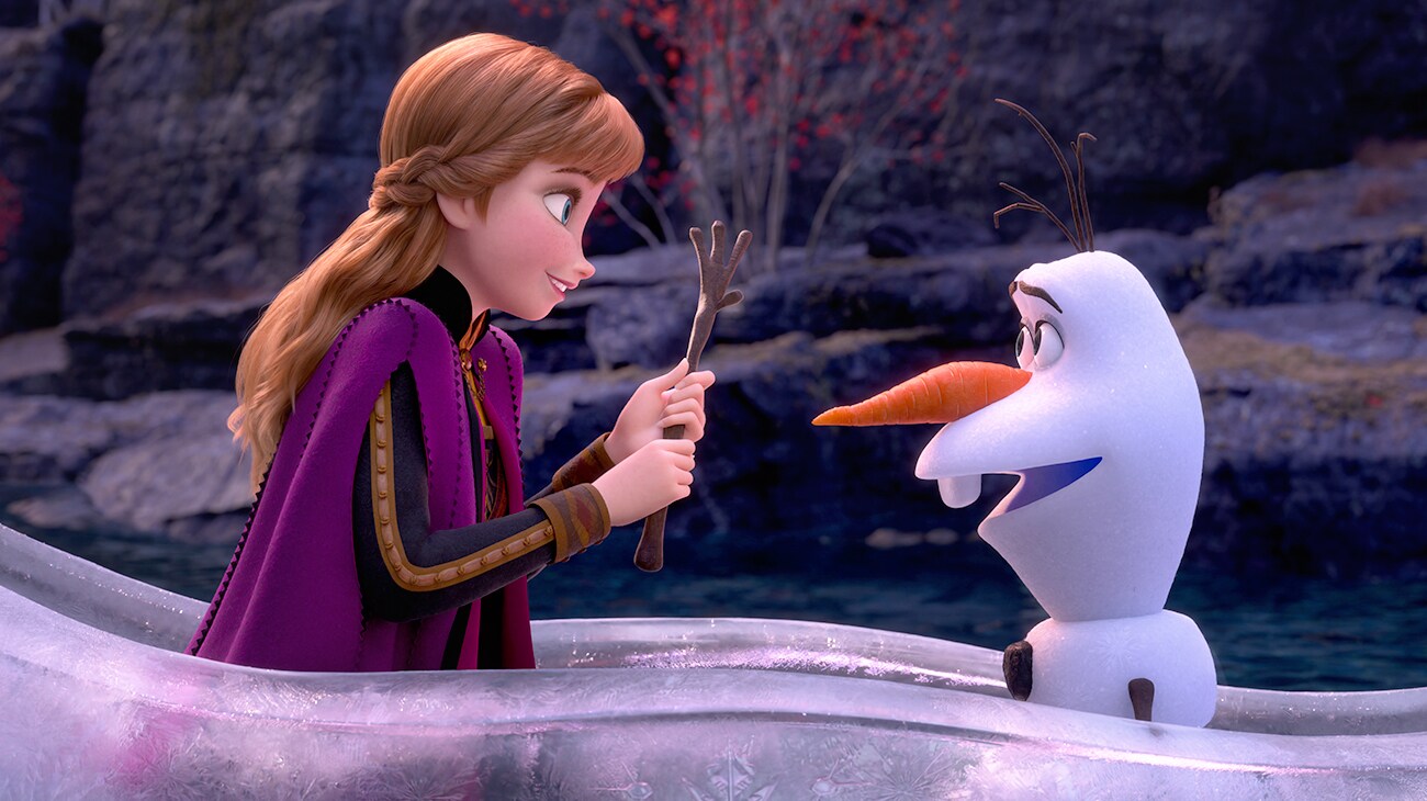 Anna (voiced by Kristen Bell) facing Olaf (voiced by Josh Gad) holding his arm in Frozen 2.