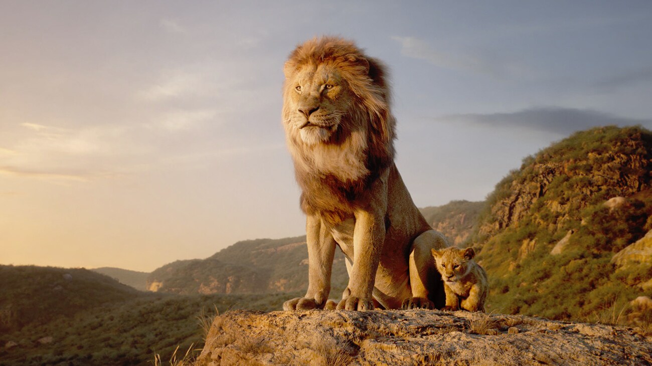 Mufasa (James Earl Jones) seated on a cliff with Simba (Donald Glover) beside him in "The Lion King"